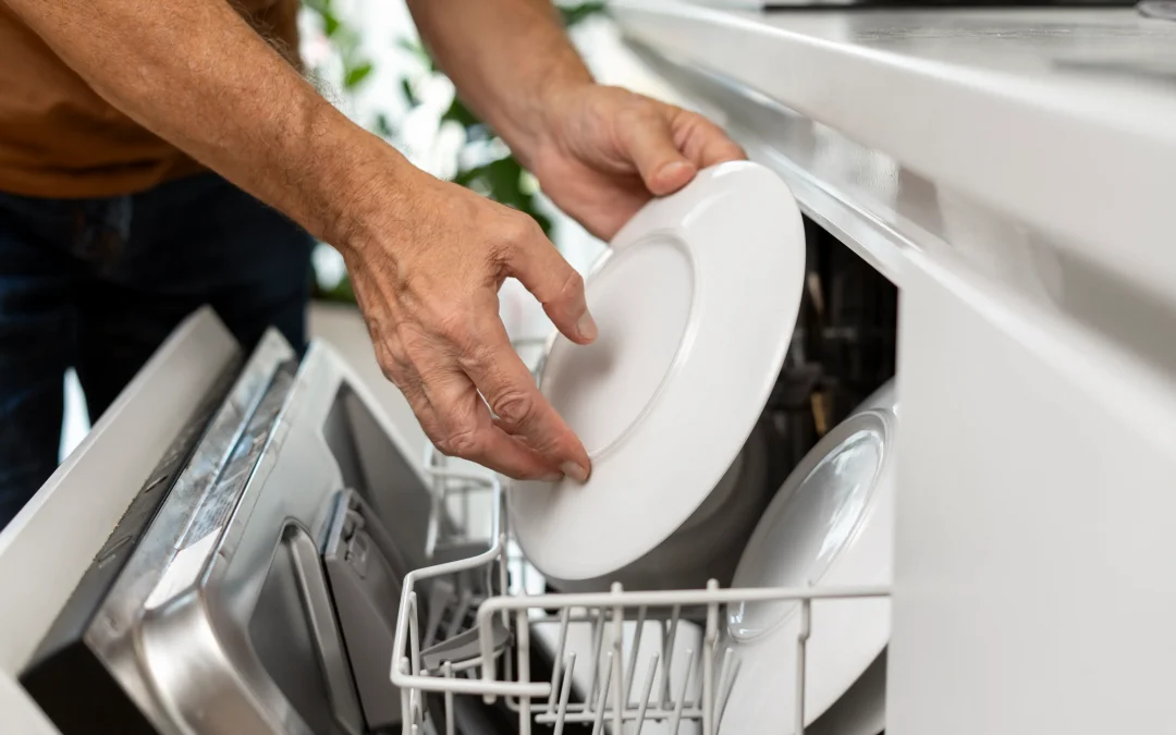 Homme charge la vaisselle dans le lave-vaisselle, pose des assiettes